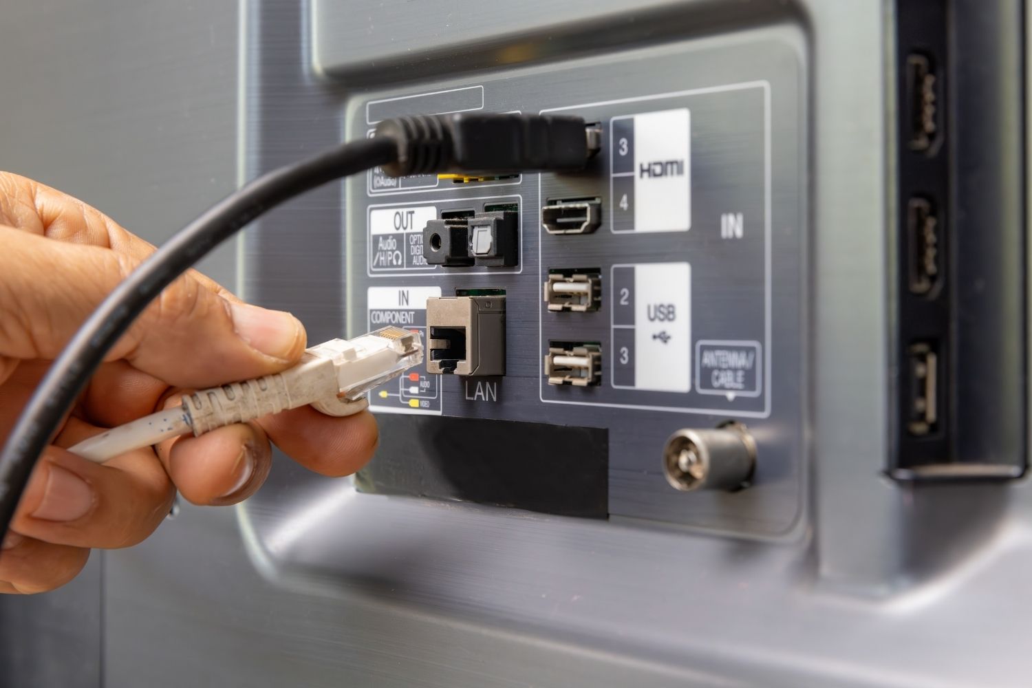 E Person steckt es Ethernet-Chabel in de LAN-Aschluss vonere IPTV Box für e stabilere Internetverbindig.